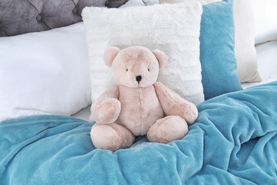 Photo of Cute teddy bear sitting on bed indoors