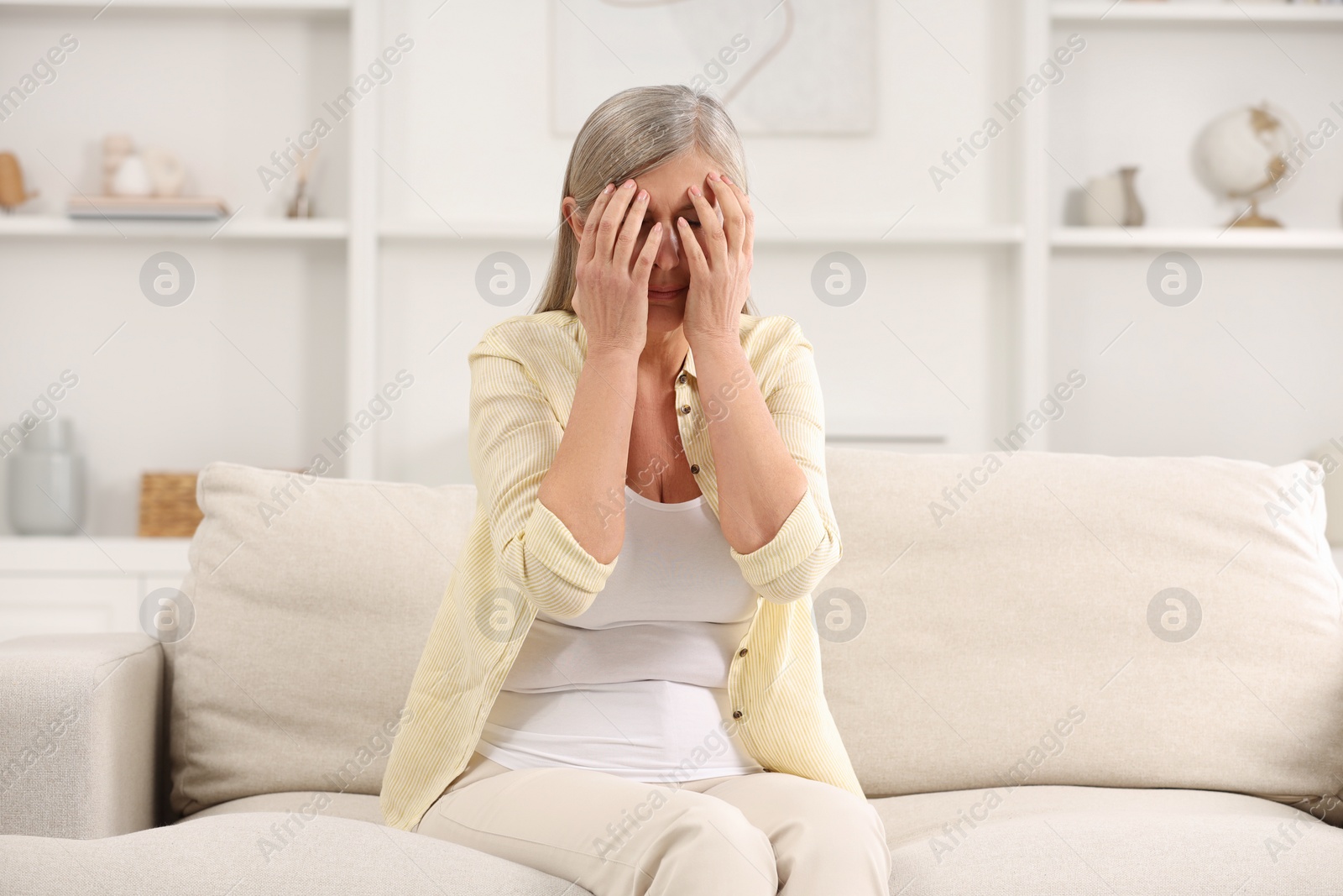 Photo of Menopause. Woman suffering from headache on sofa at home