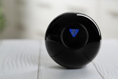 Photo of Magic eight ball with prediction Don't Bet On It on light wooden table, closeup. Space for text