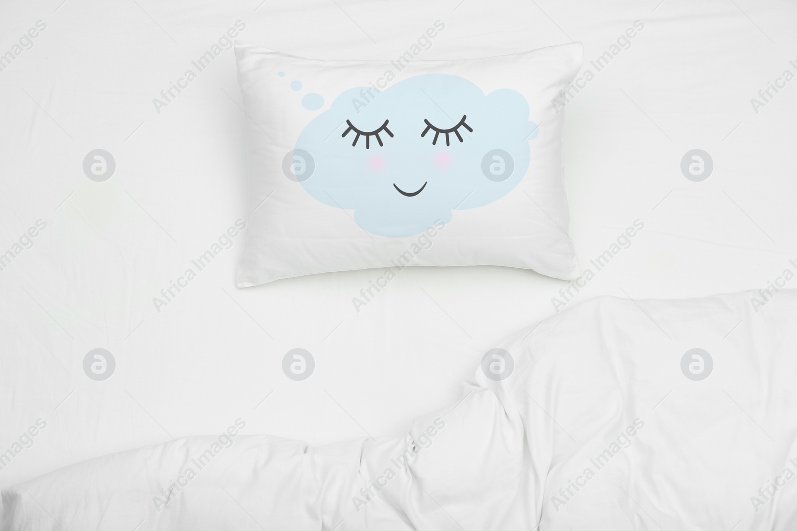 Image of Soft pillow with cute face and blanket on bed, top view