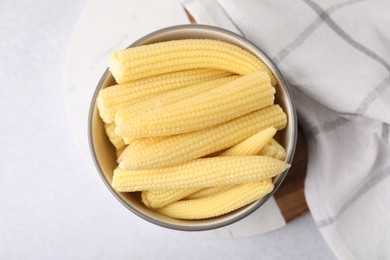 Photo of Tasty fresh yellow baby corns in bowl on white table, top view