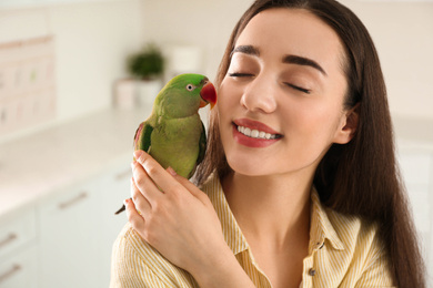 Young woman with Alexandrine parakeet indoors. Cute pet