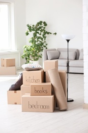 Photo of Pile of moving boxes and household stuff in living room