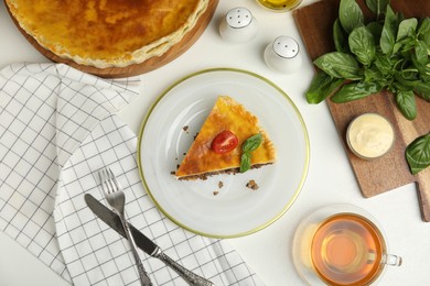 Photo of Piece of delicious pie with minced meat, tomato and tea served on white table, flat lay