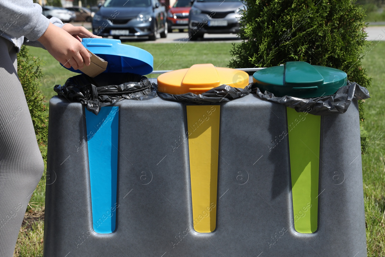 Photo of Woman throwing cardboard in bin outdoors, closeup. Recycling concept