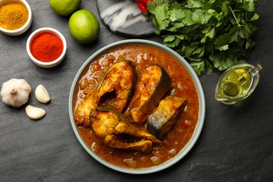 Photo of Tasty fish curry and ingredients on grey textured table, flat lay. Indian cuisine