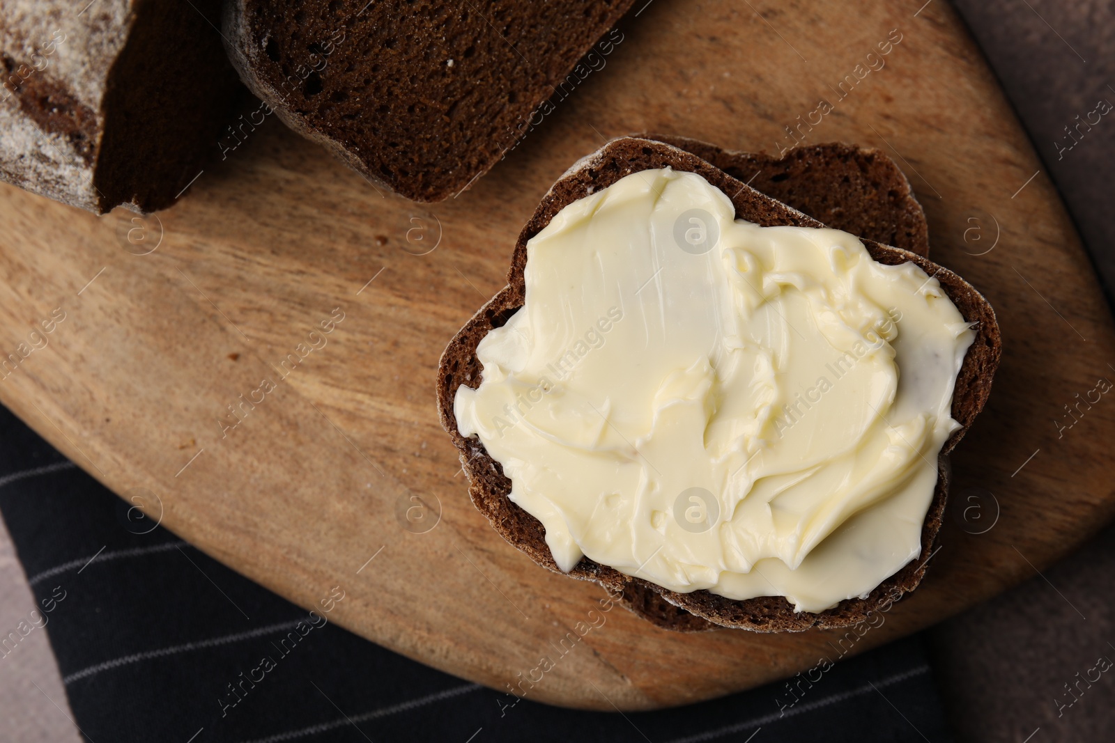 Photo of Tasty bread with butter on grey textured table, top view