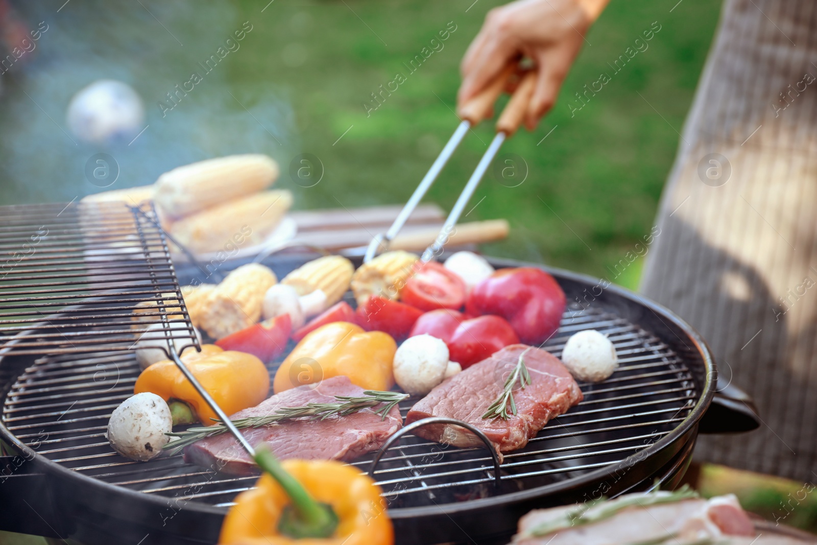 Photo of Man cooking food on barbecue grill outdoors, closeup