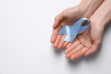 Photo of International Psoriasis Day. Woman with light blue ribbon as symbol of support on white background, top view. Space for text