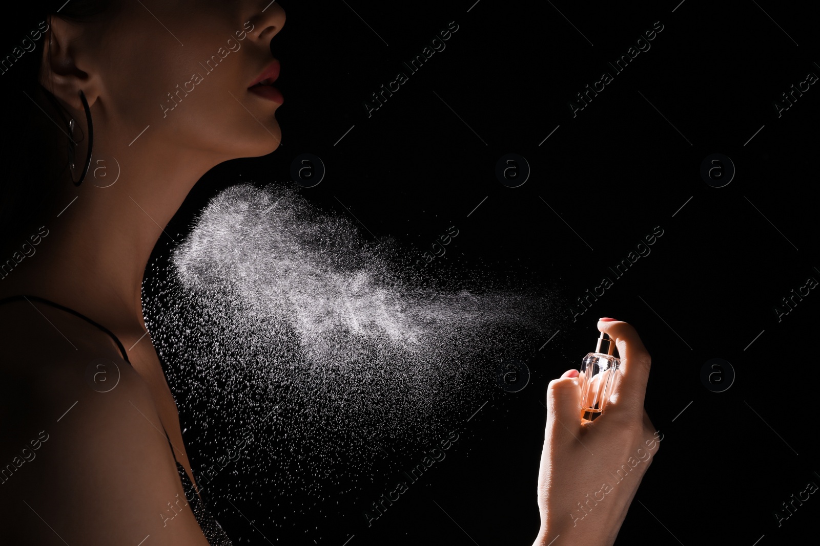 Photo of Woman spraying luxury perfume on black background, closeup