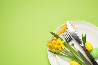 Photo of Festive Easter table setting with beautiful narcissuses and painted eggs, top view. Space for text