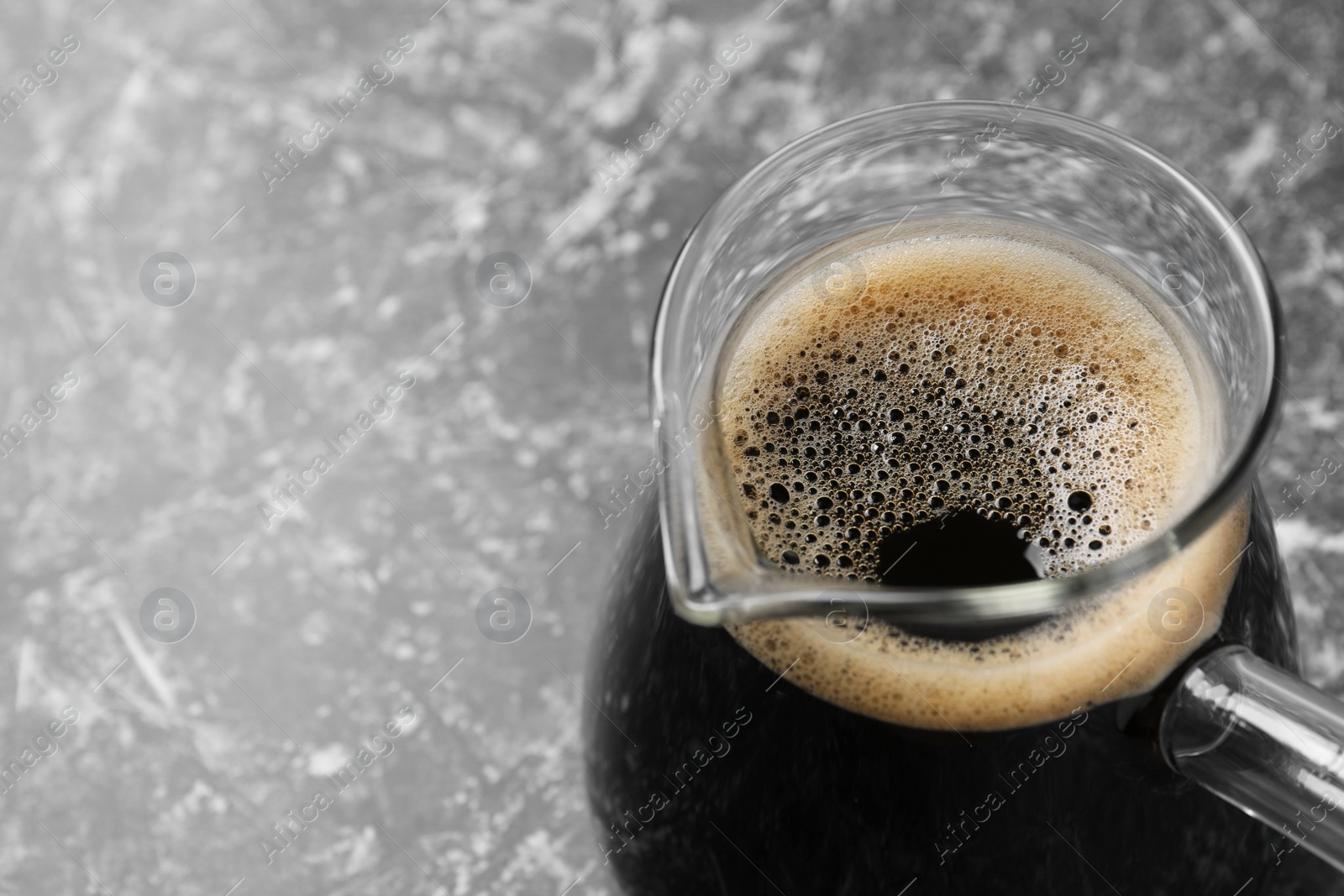 Photo of Turkish coffee in glass cezve on grey marble table, closeup. Space for text