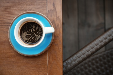 Cup of fresh aromatic coffee on wooden table, top view