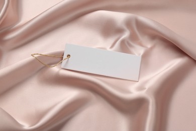 Blank white tag on pink silky fabric. Space or text