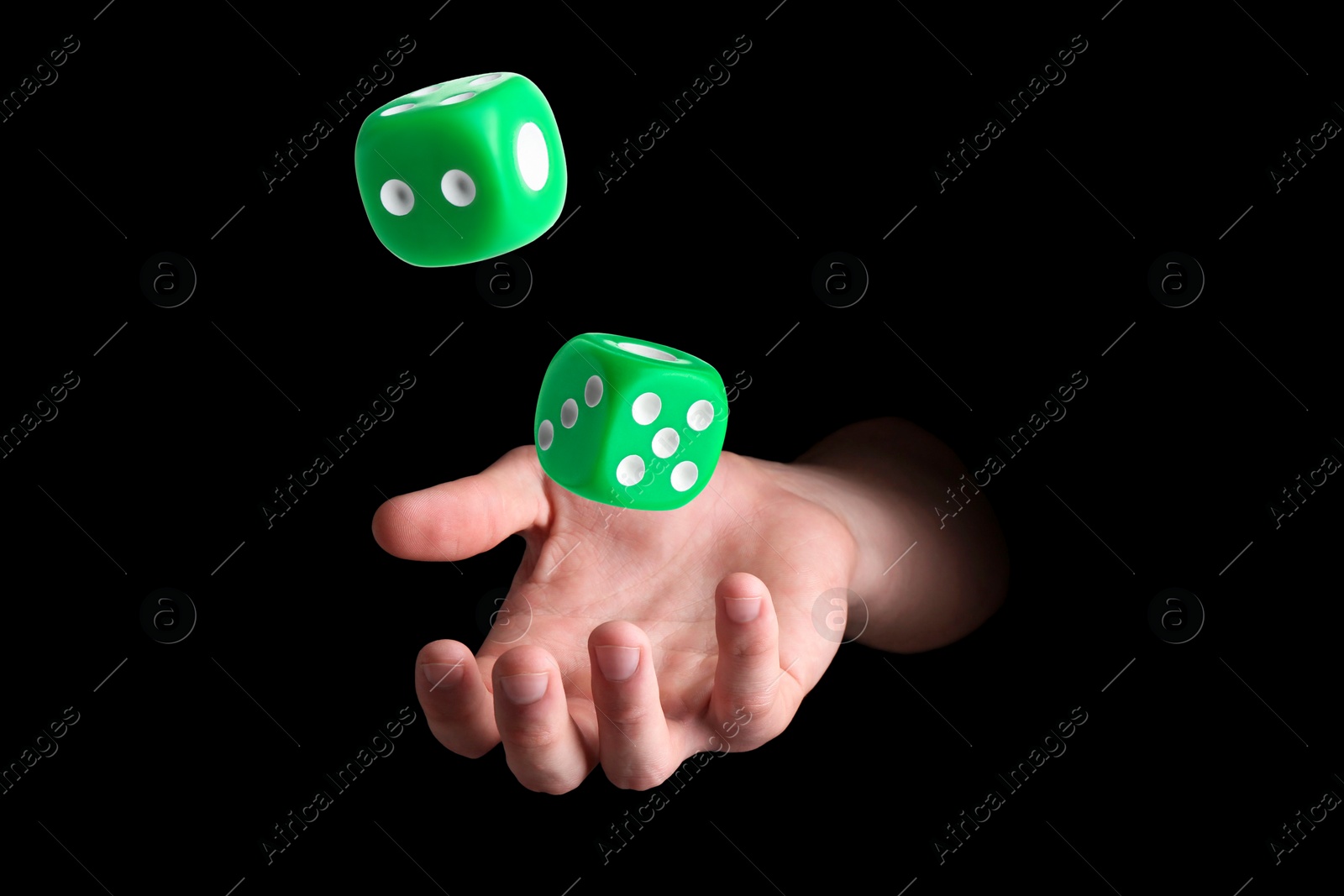 Image of Man throwing green dice on black background, closeup