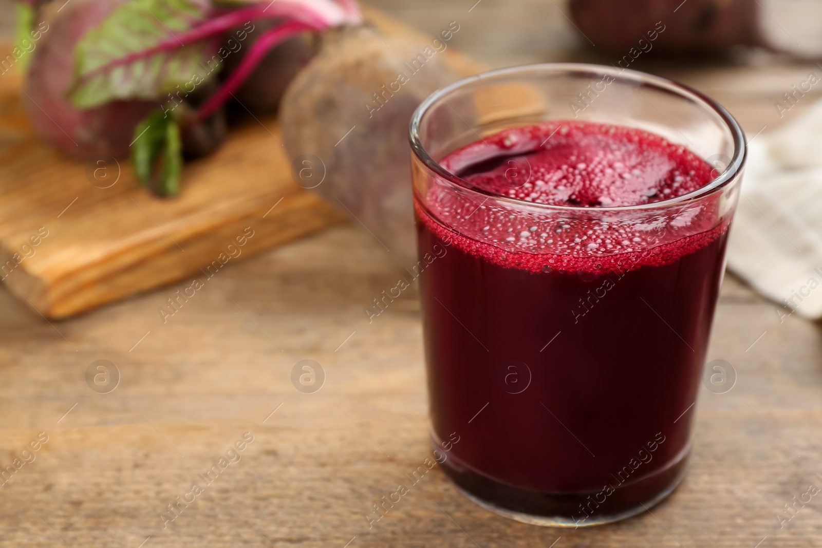 Photo of Freshly made beet juice in glass on wooden table. Space for text