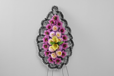 Photo of Funeral wreath of plastic flowers on grey background