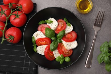 Photo of Delicious salad Caprese with tomatoes, mozzarella, basil and spices served on brown table, flat lay