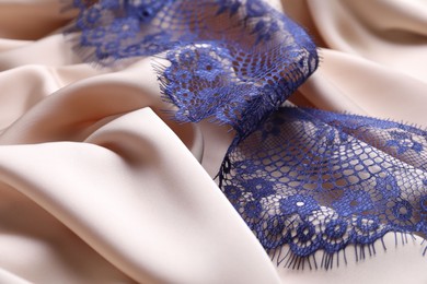 Photo of Beautiful blue lace on beige fabric, closeup