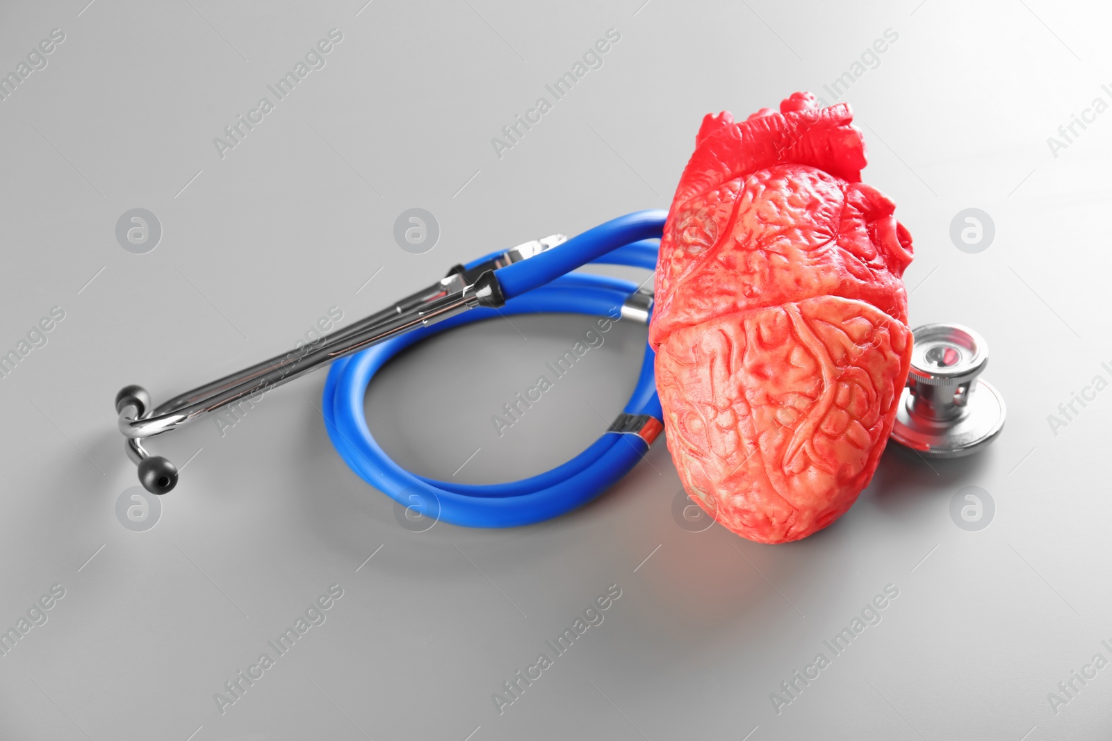 Photo of Stethoscope and model of heart on gray background. Heart attack concept