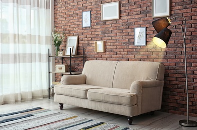 Photo of Modern living room interior with comfortable sofa near brick wall