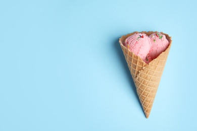 Photo of Delicious ice cream in wafer cone on blue background, top view. Space for text