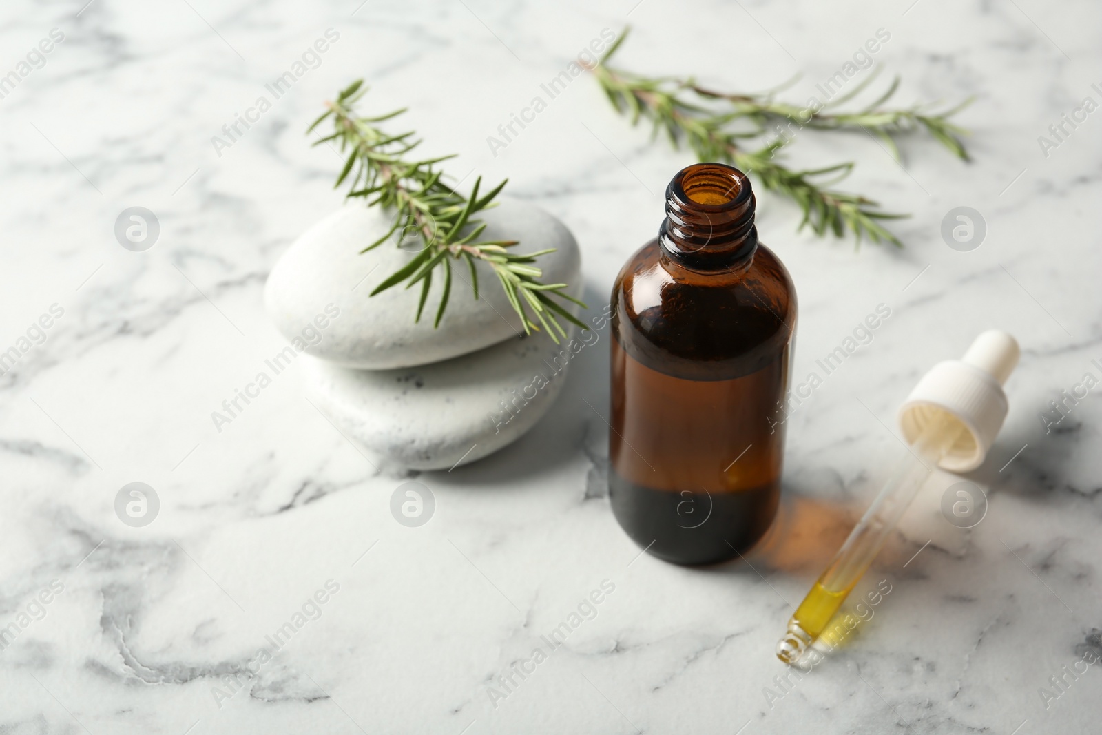 Photo of Composition with bottle of rosemary oil and fresh twigs on light table