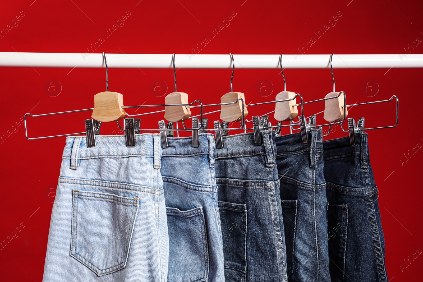 Photo of Rack with different jeans on red background