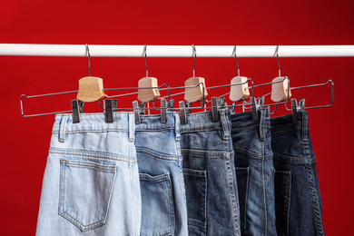 Photo of Rack with different jeans on red background