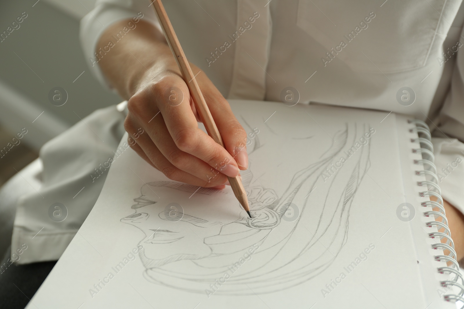 Photo of Woman drawing girl's portrait with pencil in notepad, closeup