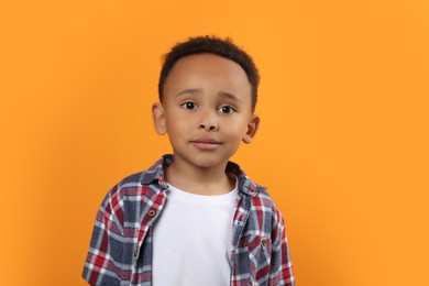 Photo of Portrait of cute African-American boy on orange background