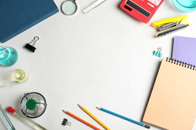 Photo of Laboratory glassware and school supplies on light background, top view with space for text