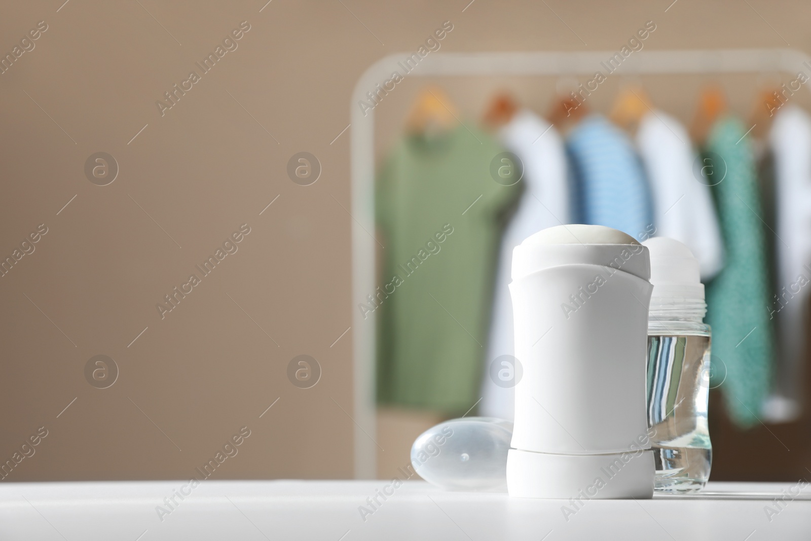 Photo of Different deodorants on white table in room. Space for text