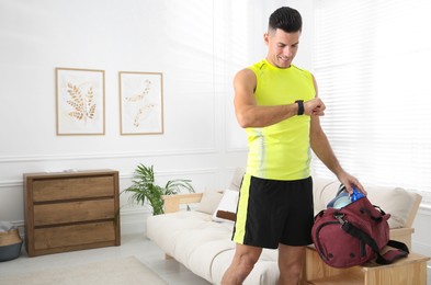 Photo of Man packing sports stuff for training into bag at home