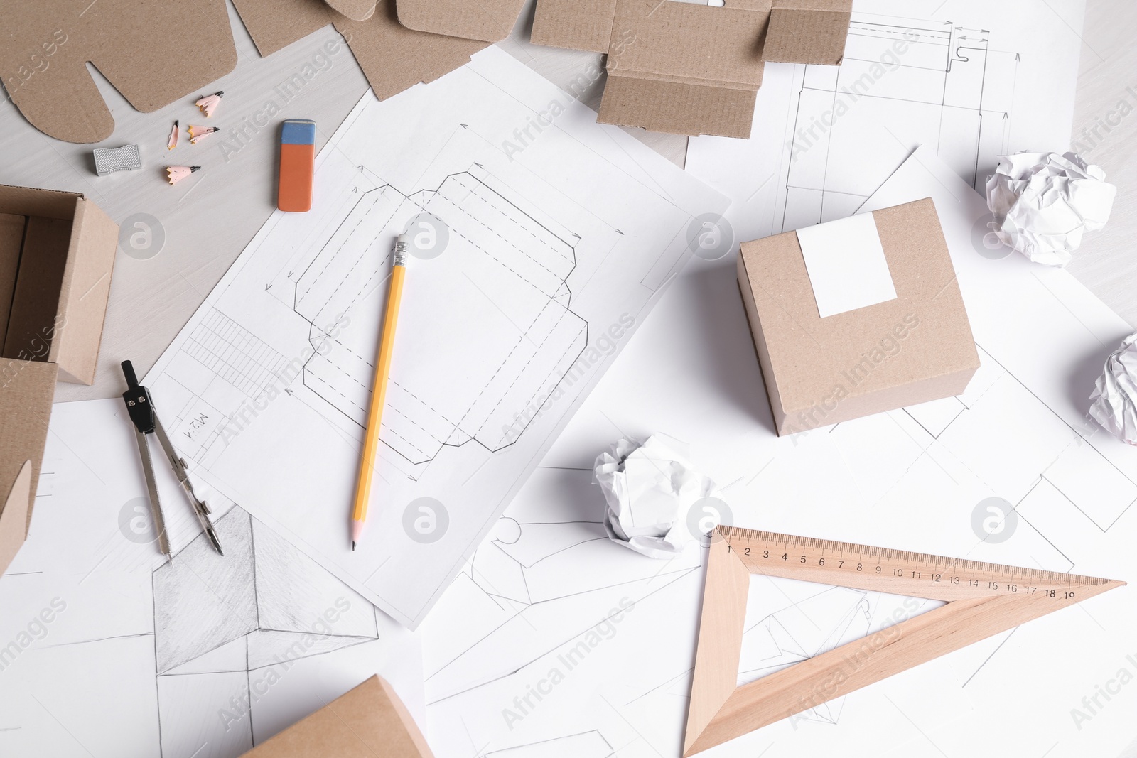 Photo of Creating packaging design. Drawings, boxes and stationery on light wooden table, flat lay