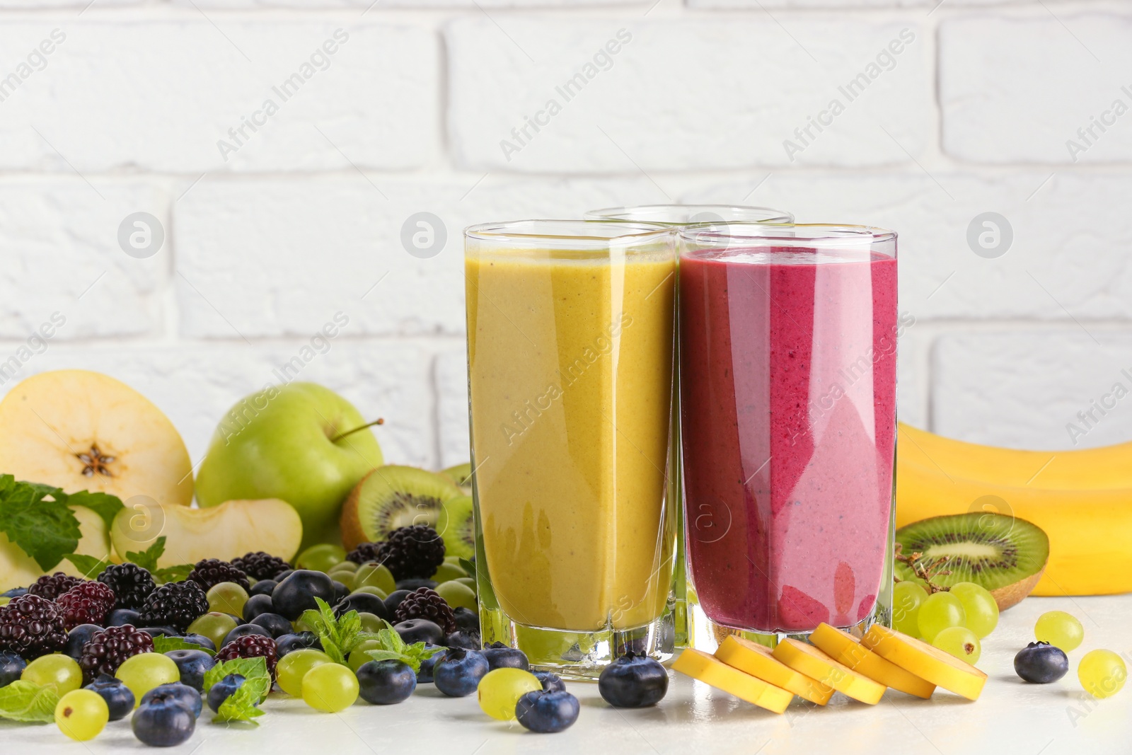 Photo of Fresh colorful fruit smoothies and ingredients on white table