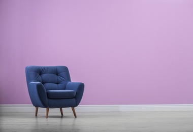 Photo of Stylish comfortable armchair near color wall