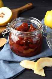 Photo of Quince jam in glass jar and fresh raw fruits on grey table, closeup