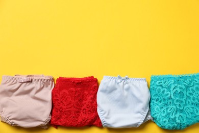 Photo of Stylish folded women's underwear on yellow background, flat lay. Space for text