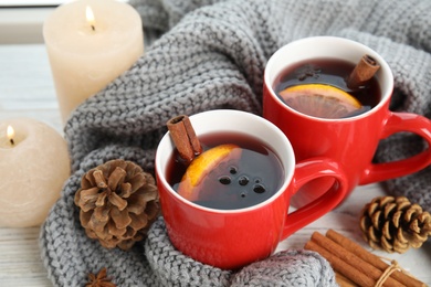 Photo of Cups of hot winter drink with knitted sweater on table