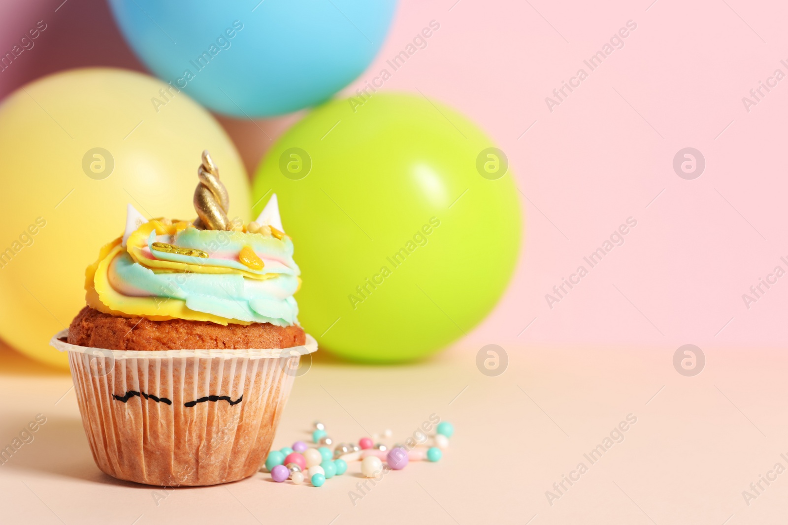 Photo of Cute sweet unicorn cupcake on beige background. Space for text