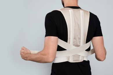 Closeup of man with orthopedic corset on grey background, back view