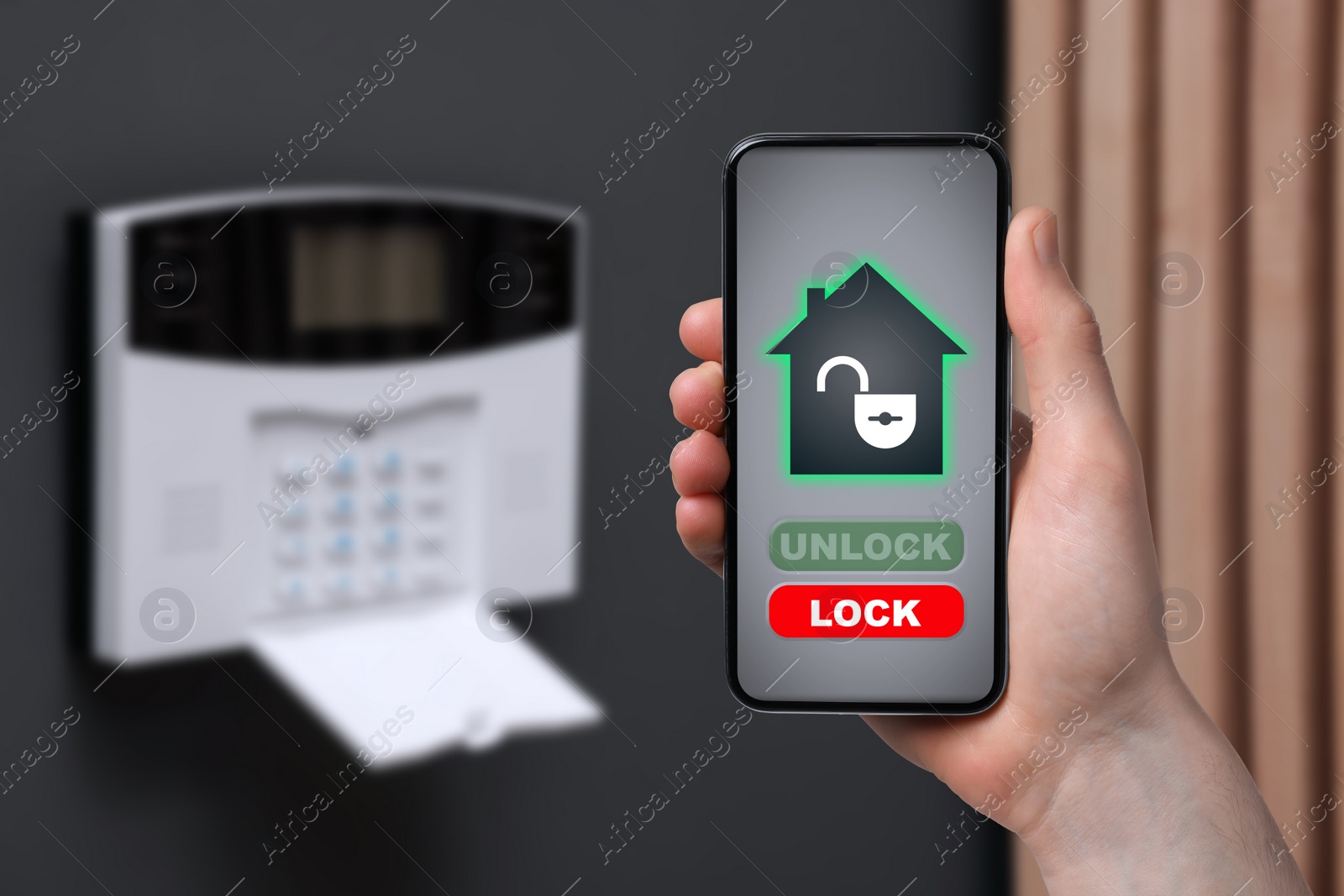 Image of Man operating home alarm system via mobile phone against dark wall with security control panel, closeup. Application interface on device screen