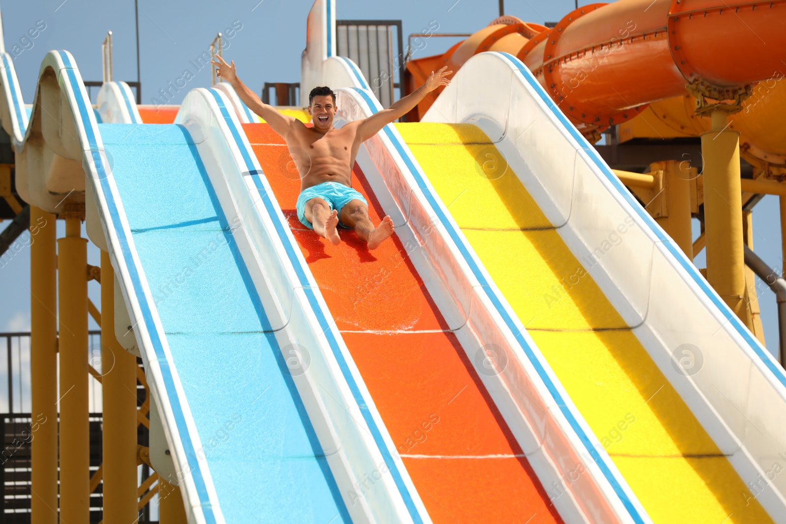 Photo of Man on slide at water park. Summer vacation