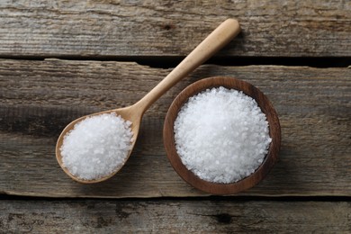 Photo of Organic salt in bowl and spoon on wooden table, flat lay