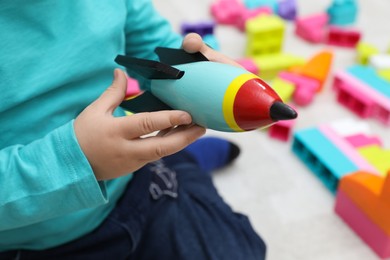 Photo of Little child playing with toy rocket indoors, closeup