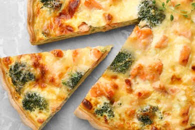 Delicious homemade quiche with salmon and broccoli on light gray table, top view