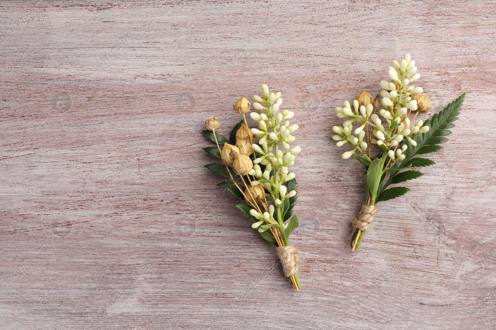 Photo of Small stylish boutonnieres on light wooden table, top view. Space for text