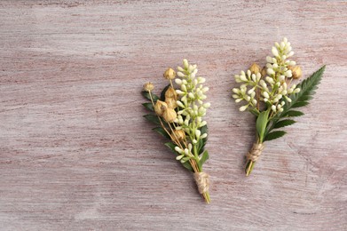 Photo of Small stylish boutonnieres on light wooden table, top view. Space for text