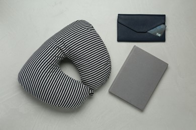 Striped travel pillow, notebook and wallet with credit card on gray background, flat lay